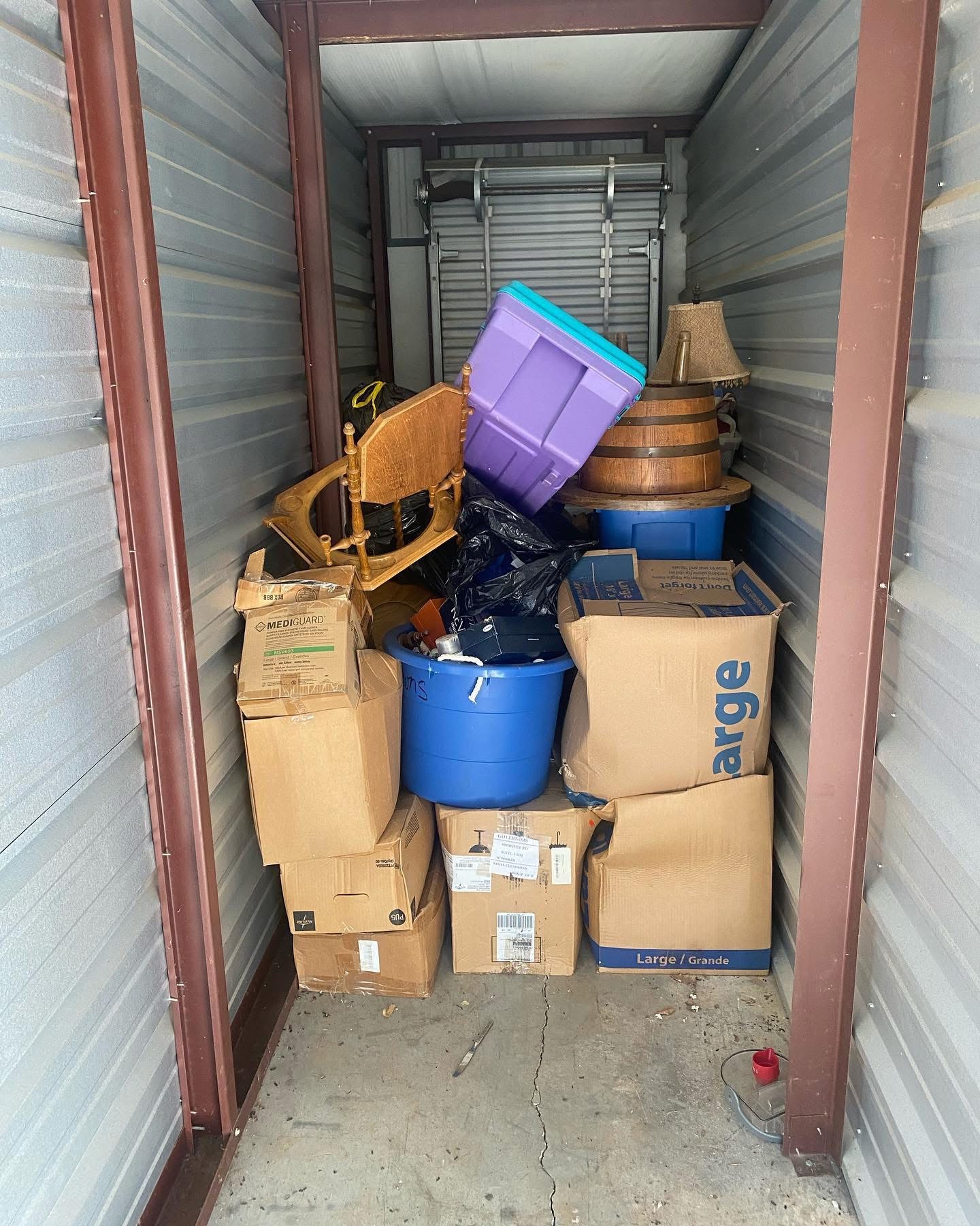 Packed storage unit with boxes, bins and furniture before Junk Ranger cleared it
