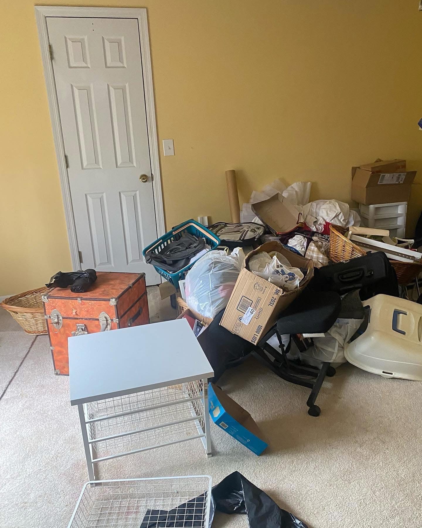 Cluttered bedroom with furniture, bags and boxes before a Junk Ranger cleanout